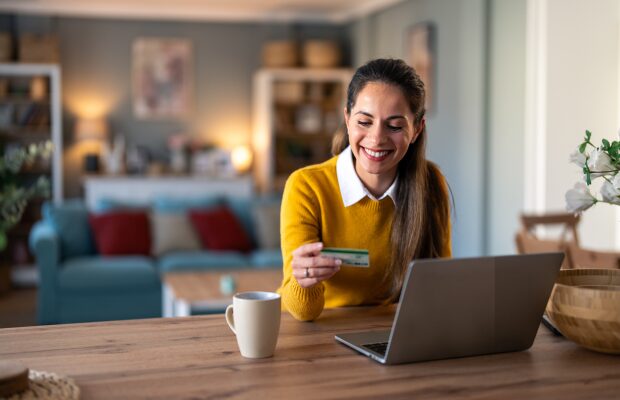 Smiling woman checking her card details while applying for a mortgage on her laptop