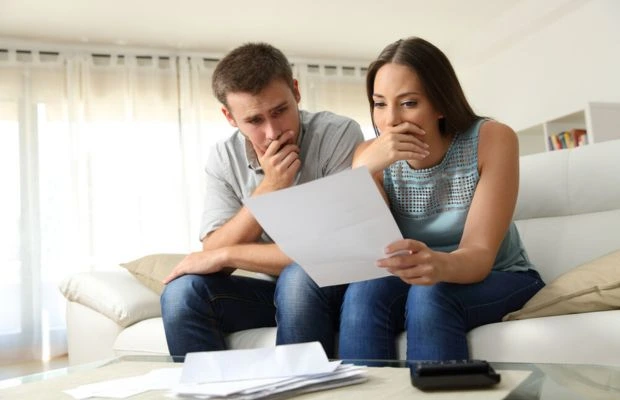 Couple sitting on a couch examining a document