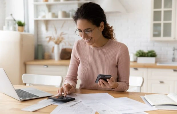 Woman using calculator laptop and papers on table