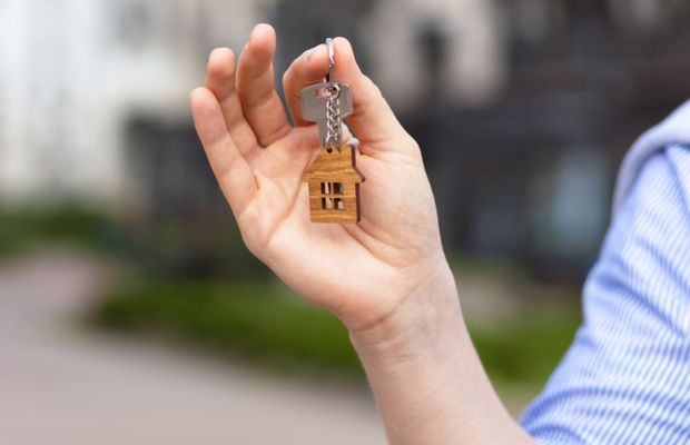 Hand holding a wooden house shaped keychain